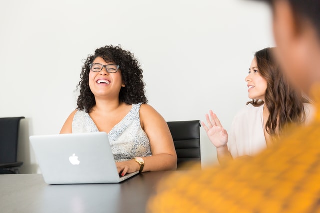 Woman with laptop laughing in meeting